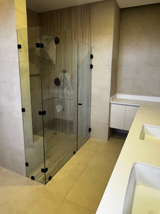 Cerramiento transparente con bisagras y accesorios oscuros.