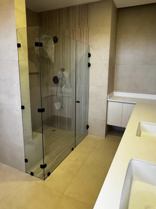Cerramiento transparente con bisagras y accesorios oscuros.