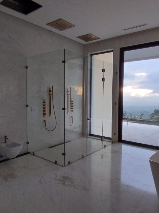 Cerramiento de vidrio para una ducha doble en un baño con ventanales amplios.