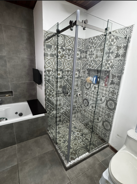 Puertas corredizas de vidrio en una ducha con revestimiento de patrones decorativos.