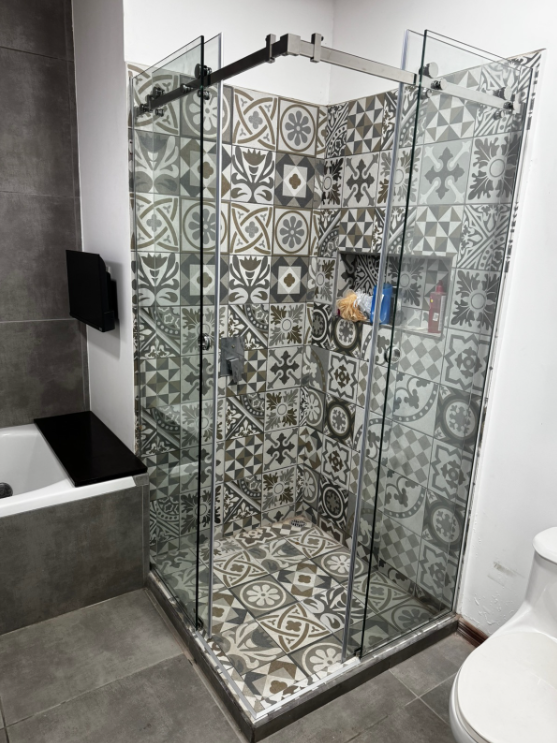 Otra vista del cerramiento de ducha con sistema corredizo y revestimiento decorativo.
