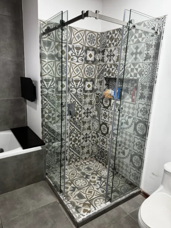 Otra vista del cerramiento de ducha con sistema corredizo y revestimiento decorativo.