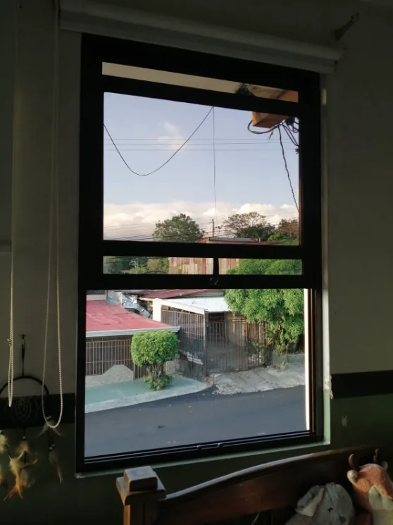 Ventana guillotina de marco oscuro instalada en una habitación.