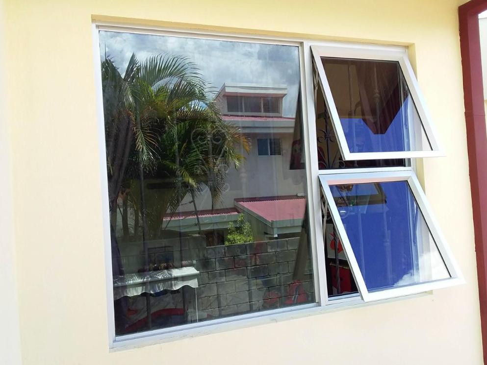 Ventana de marco claro con paño amplio y dos hojas abiertas hacia afuera.