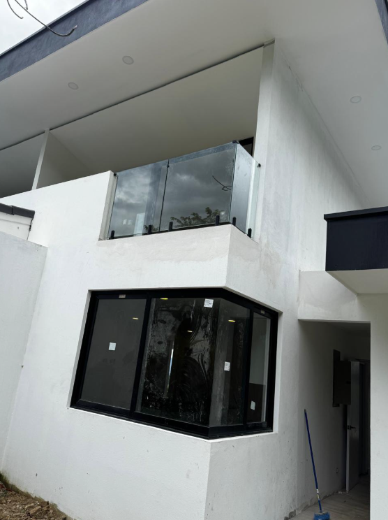 Vista exterior de ventana de esquina y balcón con vidrio en una vivienda.
