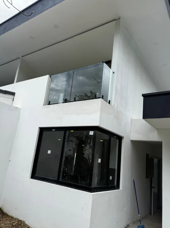 Vista exterior de ventana de esquina y balcón con vidrio en una vivienda.